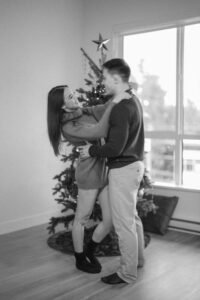 Black and white slow-shutter photo capturing the energy and movement of a couple dancing by a Christmas tree.