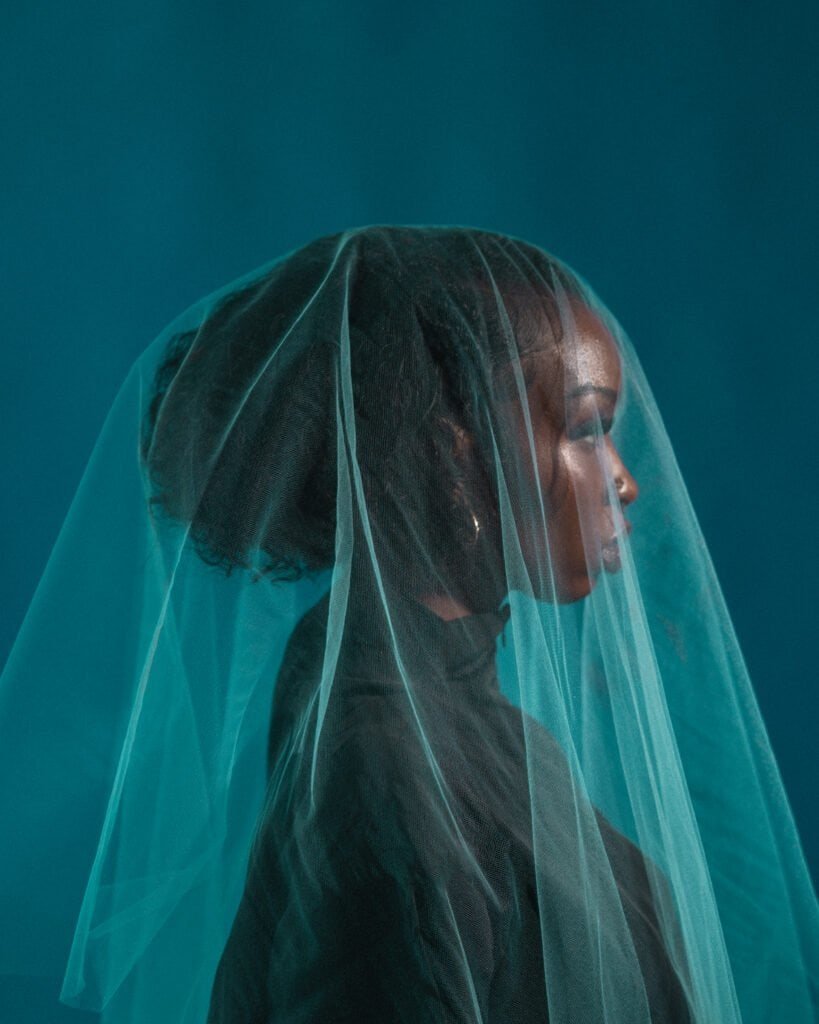 A veiled model gazes softly during a portrait photography session with Zur Photography, showcasing the artistry of veil and light.