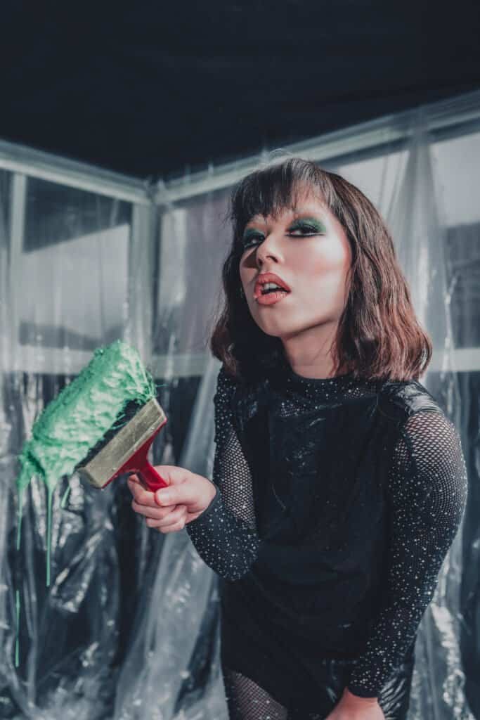 High-fashion editorial photo of TikTok influencer Tamara Steeves holding a paint brush dripping with seagreen paint, symbolizing painting her own future, at a Richmond studio, concept by Yar Tareen (Zur Photography).